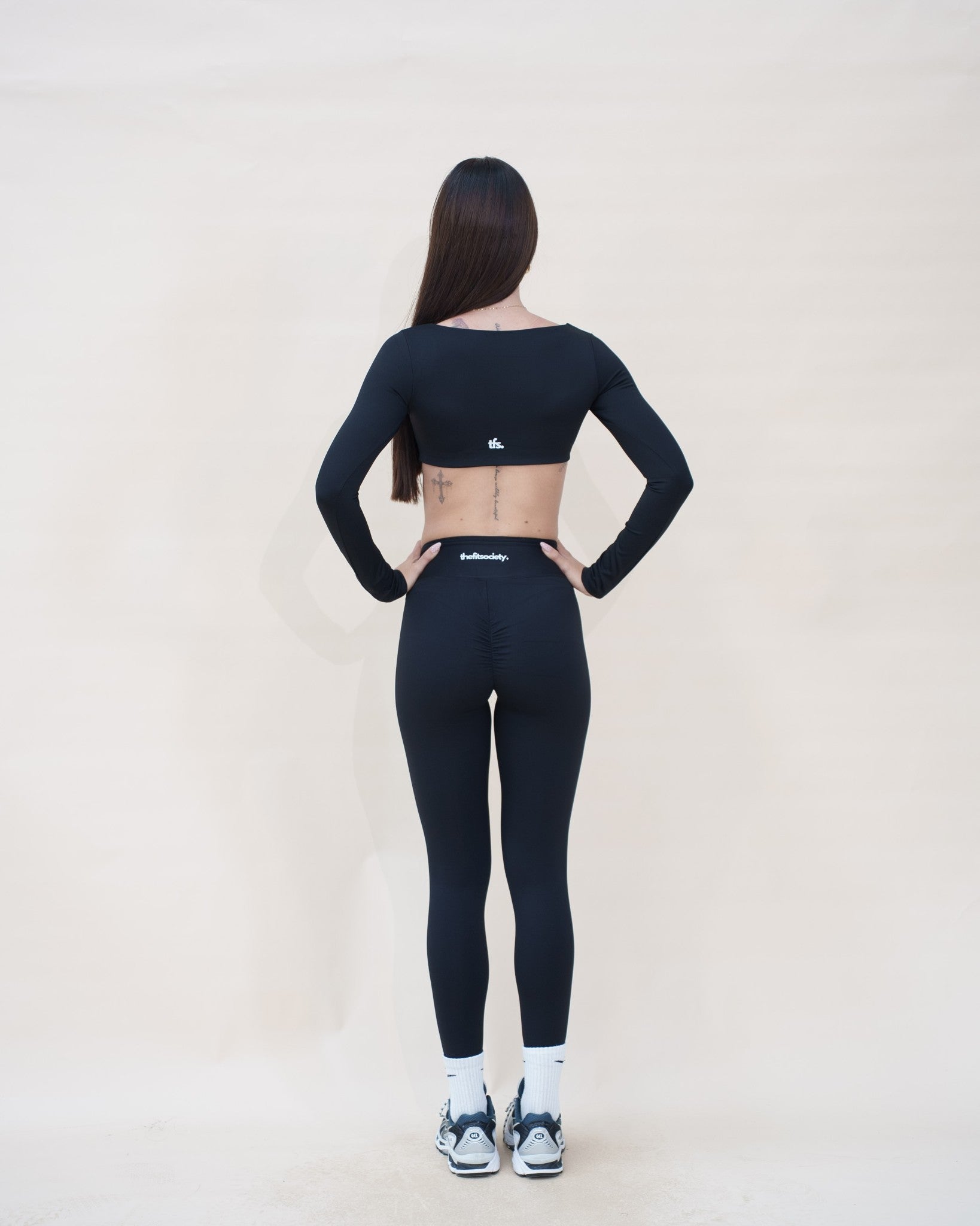 Le vestiaire Studio The Fit Society — haut noir porté avec The Studio Legging, de dos